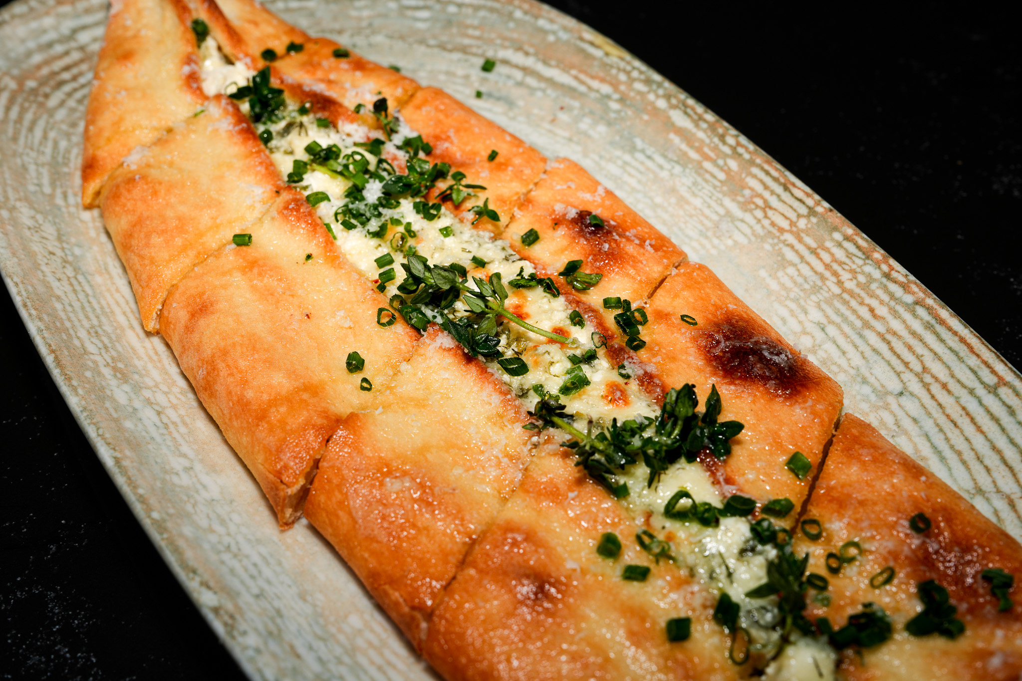Cheese pide topped with chopped herbs