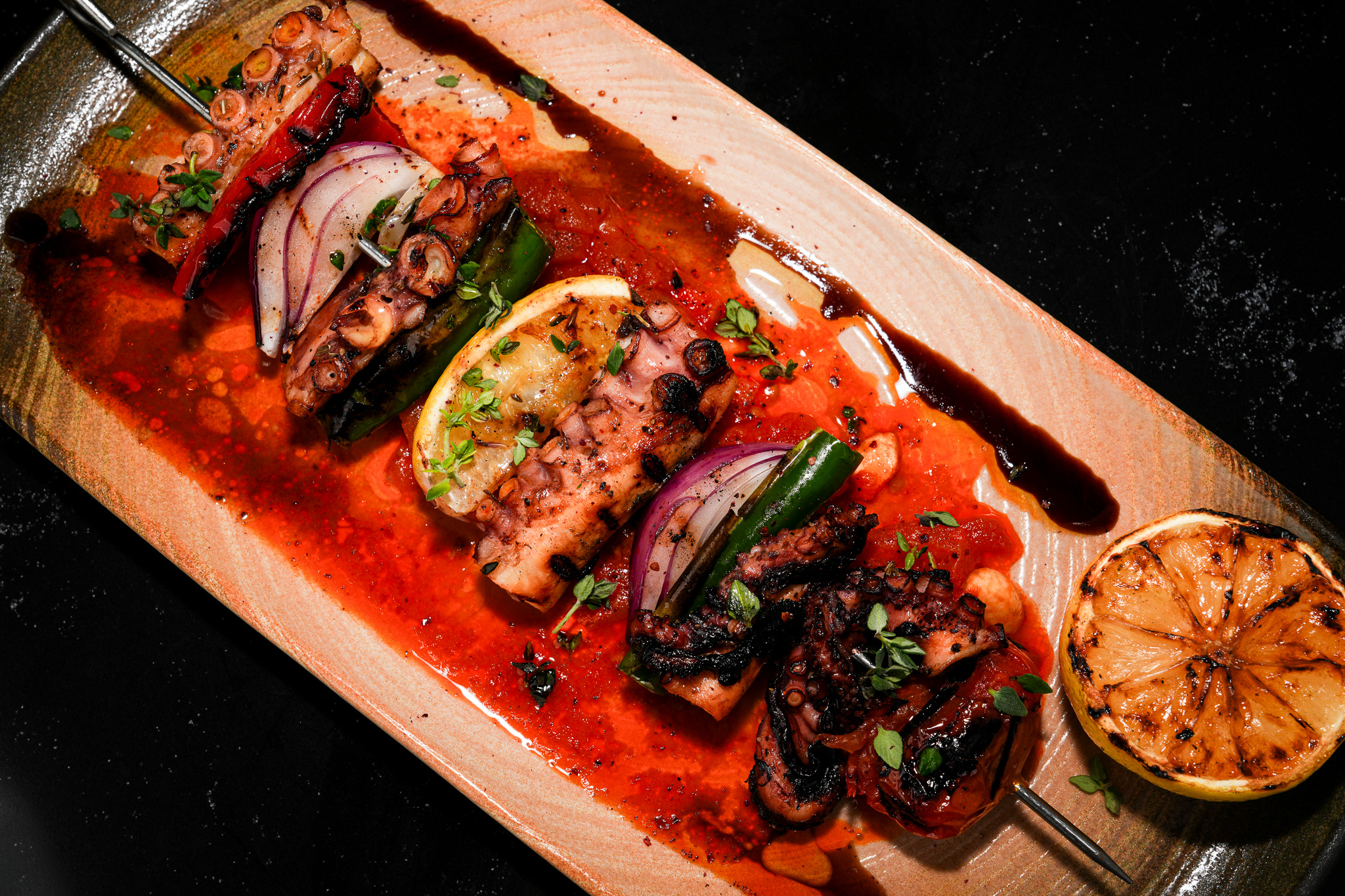 Grilled meat in tomato sauce with onion, peppers, and charred lemon