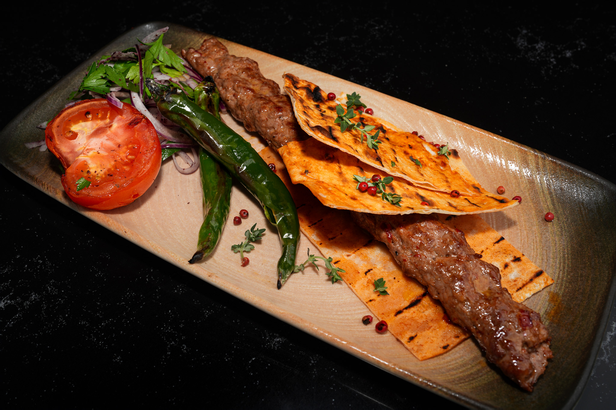 Long grilled kebab with flatbread, tomato, and green pepper