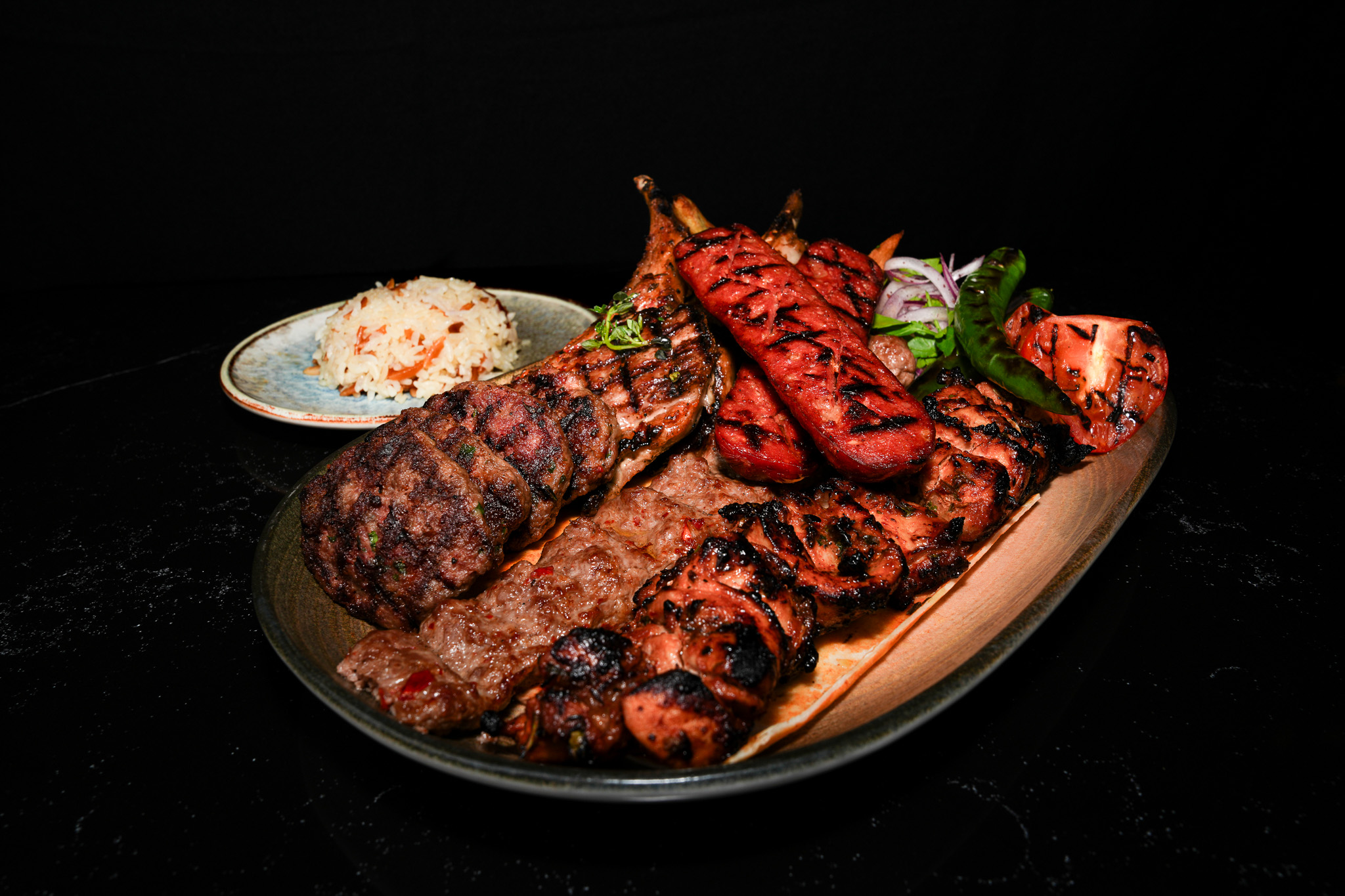 Mixed grill platter with rice, tomato, and green pepper, viewed from above