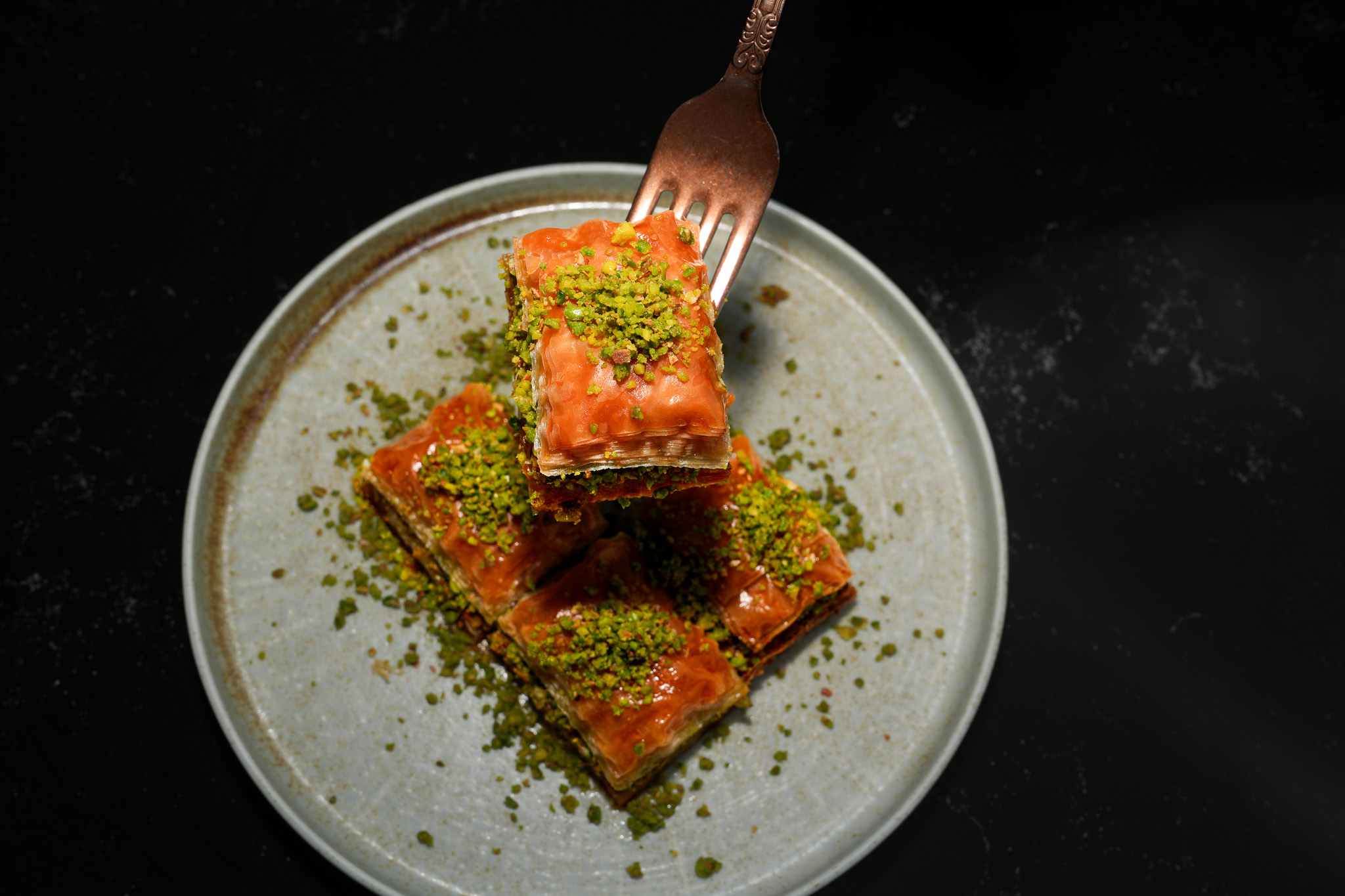 A fork lifting a piece of pistachio baklava