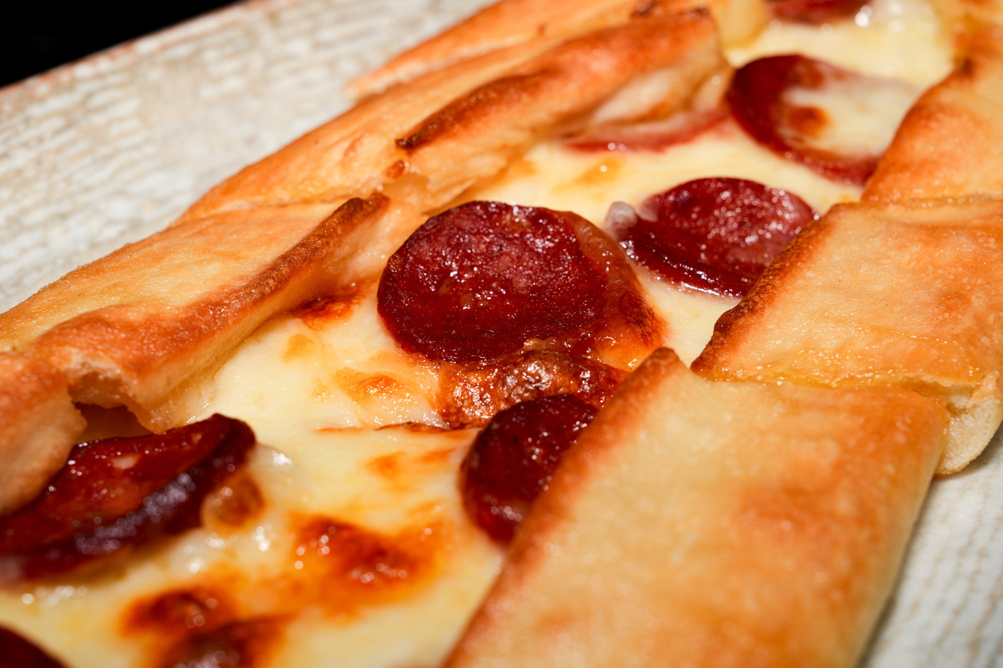 Close-up of sausage slices and melted cheese inside pide