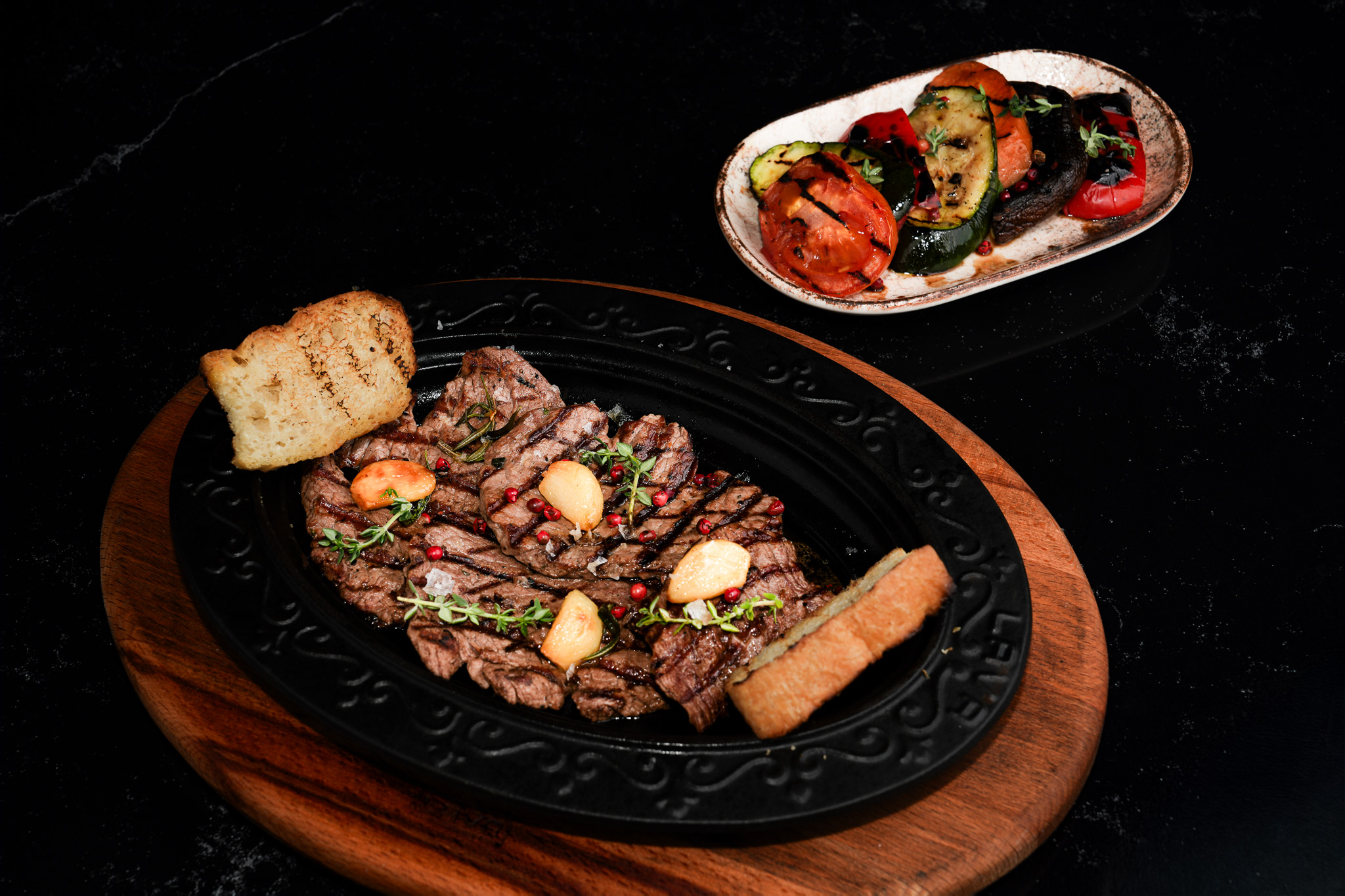 Steak platter with toasted bread and a side of grilled vegetables